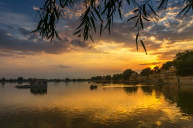 Spectacular sunset at Gadisar lake,Jaisalmer,Rajasthan, India. Setting sun and colorful clouds in the sky with view of the Gadisar lake. Connected with Indira Gandhi Canal for continuous water supply.