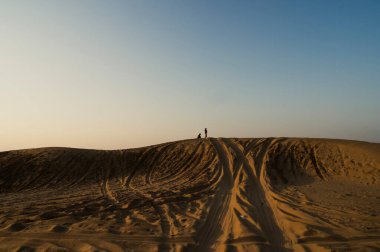 Thar Çölü, Rajasthan, Hindistan 'daki kum tepelerinde araba lastiği izleri var. Turistler, gezginler arasında çok popüler bir etkinlik olan çölde güneşin doğuşunu izlemek için arabalarla geliyorlar..