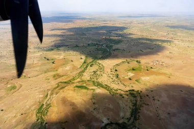 Hindistan, Rajasthan 'daki bir uçaktan Thar Çölü manzarası. Çerçevedeki pervaneler ve çöl. Aşağıdaki çölde güneş ışığı ve bulutların gölgesi.