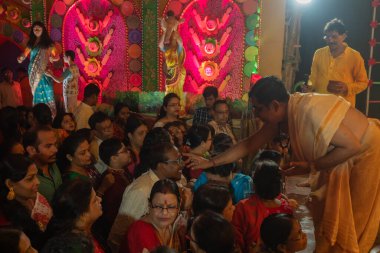 Howrah, Batı Bengal, Hindistan - 3 Ekim 2022: Hindu purohit çizimi tilak, tanrıça Durga 'ya tapanların alnında kutsal işaret, gece Durga Puja Pandalı' nın içinde. Durga puja.