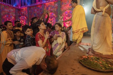 Howrah, West Bengal, India - 3rd October, 2022 : Hindu Bengali sari clad women praying to Goddess Durga inside Durga Puja pandal. Ashtami puja aarati at night. Biggest fetsival of Hinduism. clipart