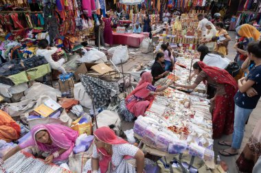 Jodhpur, Rajasthan, Hindistan - 20.10.2019: Beyaz kolyeler, altın kaplama küpeler ve süsler Jodhpur 'daki ünlü Sardar Market ve Ghanta ghar saat kulesinde genç bayan müşterilere satılıyor.