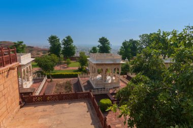 Beautiful decorated garden of Jaswant Thada cenotaph. Garden has carved gazebos, a tiered garden, and a small lake with nice view. Thar desert and blue sky background. clipart