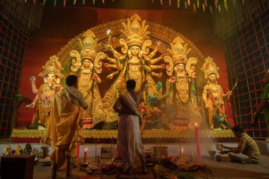 Howrah, West Bengal, India - 3rd October, 2022 : Hindu Priests worshipping Goddess Durga with conch shell. Ashtami puja aarati - sacred Durga Puja ritual- festival of Hinduism being performed at night. clipart