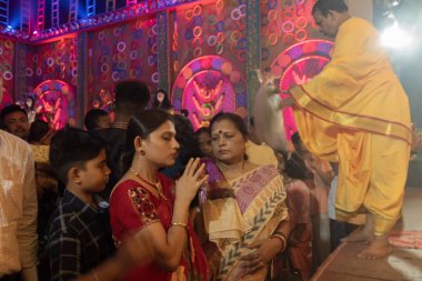 Howrah, Batı Bengal, Hindistan - 3 Ekim 2022: Hindu Bengali sarili kadın, Durga Puja Pandali 'nin içinde elleri bağlı tanrıça Durga' ya dua ediyor. Hinduizm 'in en büyük fetsivası.