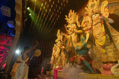 Howrah, Batı Bengal, Hindistan - 3 Ekim 2022: Hindu rahipler Tanrıça Durga 'ya aynayla tapıyorlar ki Tanrıça elbisesini görebilsin. Ashtami puja aarati - Durga Puja ritüeli - Hinduizm festivali.