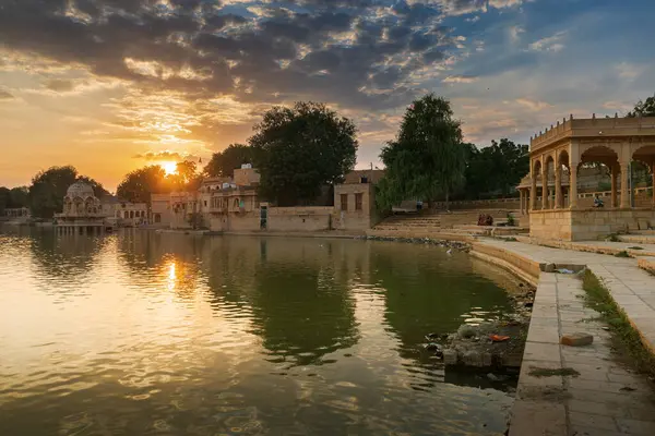 stock image Nice sunset at Gadisar lake, Jaisalmer, Rajasthan, India. Setting sun and colorful clouds in the sky with view of the Gadisar lake. Connected with Indira Gandhi Canal for continuous water supply.