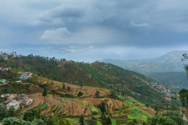 Step agriculture, or terrace agriculture. Steep hills or mountainsides are cut to form level areas for planting of crops. Foggy, misty Himalayan mountains background, Garhwal, Uttarakhand, India. clipart