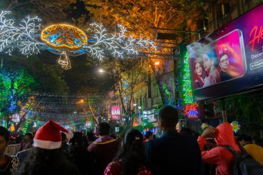 Kolkata, West Bengal, India - 25.12.2018 : Young people enjoying themselves at illuminated and decorated park street with lights with year end festive mood. Night sky background. clipart