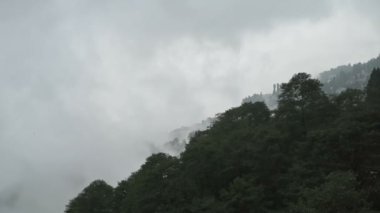 Hindistan, Batı Bengal, Darjeeling 'deki Himalaya dağlarının üzerinden geçen muson bulutlarının yavaş çekim videosu. Darjeeling, tepelerin kraliçesi ve yağmurlu mevsimde güzel yeşil tepeleri olan çok manzaralı bir yerdir..