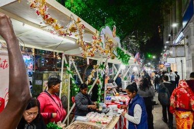 Kolkata, Batı Bengal, Hindistan - 24,12,2023: Park Caddesi 'nde Noel boyunca lezzetli yemek ve atıştırmalıkların tadını çıkaran vatandaşlar. İnsanlar Noel 'de eğlenmek için Park Caddesini ziyaret ediyor..