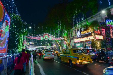 Kolkata, Batı Bengal, Hindistan - 24.12.2023: Park Caddesi 'nde Noel ışıklandırması. Kolkata 'nın ünlü sarı taksisi gece aydınlık caddede. Vatandaşlar eğlence ve gece hayatının tadını çıkarmak için Park Caddesini ziyaret ediyor..