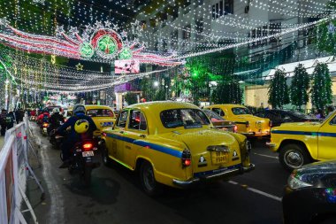 Kolkata, Batı Bengal, Hindistan - 24.12.2023: Park Caddesi 'nde Noel ışıklandırması. Meşhur sarı taksiler geceleri işlek Park Caddesinde parlıyordu. Vatandaşlar eğlence ve gece hayatının tadını çıkarmak için Park Caddesini ziyaret ediyor..