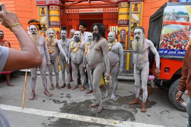 Haridwar, Uttarakhand, India - 13th April 2021 : Hindu naked sadhus, naga babas, getting framed before holy bathe called shahi snaan on river Ganges and shouting Har Har Mahadev. Kumbhmela event. clipart