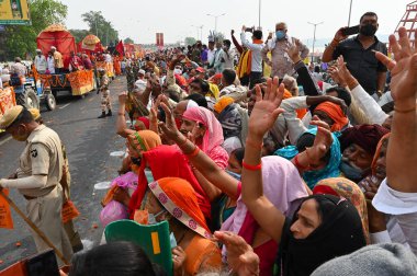 Haridwar, Uttarakhand, India - 13th April 2021 : Hindu sadhus, sanyasis in saffron dresses on tractors in procession for shahi snaan on Holy river Ganges. Maha Kumbhmela, devotees cheering for them. clipart