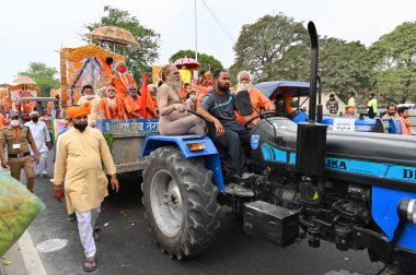 Haridwar, Uttarakhand, India - 13th April 2021 : Hindu sadhus, sanyasis in saffron dresses on tractors in procession for shahi snaan on Holy river Ganges. Maha Kumbhmela event, Hinduism in India. clipart