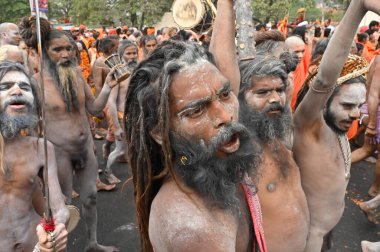 Haridwar, Uttarakhand, India - 13th April 2021 : Hindu naked sadhus, naga babas, naga sanyasis blessing devotess before having shahi snaan on river Ganges and shouting Har Har Mahadev.Kumbhmela event. clipart