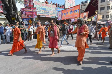 Haridwar, Uttarakhand, India - 15th April 2021 : Sadhus, sanyasis in saffron dresses walking on road in procession for shahi snaan on Holy river Ganges. Maha Kumbhmela event, Hinduism in India. clipart