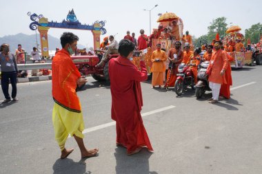 Haridwar, Uttarakhand, Hindistan - 16 Nisan 2021: Grup fotoğrafı çekiliyor. Hindu keşişler, sadhular, parlak safran elbiseli sanyasiler bisiklete binip Ganj Nehri 'ndeki Shahi Snaan' a gidiyorlar..