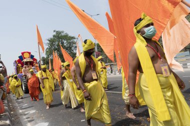 Haridwar, Uttarakhand, Hindistan - 16 Nisan 2021: Maha Kumbhmela etkinliği. Sadhus, parlak safran bayraklarıyla sarı elbiseli sanyasiler kutsal Ganj nehrinde shahi snaan yemek için yürüyorlar..