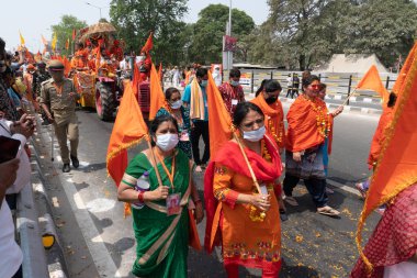 Haridwar, Uttarakhand, Hindistan - 16 Nisan 2021: Hindu kadınlar Ganj Nehri 'nde shahi snaan yemek için geçit töreninde ellerinde bayraklar tutan maskeli kadınlar. Kutsal Maha Kumbhmela etkinliği.