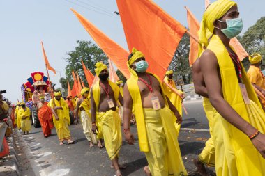 Haridwar, Uttarakhand, Hindistan - 16 Nisan 2021: Maha Kumbhmela etkinliği. Sadhus, parlak safran bayraklarıyla sarı elbiseli sanyasiler kutsal Ganj nehrinde shahi snaan yemek için yürüyorlar..