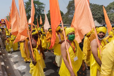 Haridwar, Uttarakhand, Hindistan - 16 Nisan 2021: Maha Kumbhmela etkinliği. Sadhus, parlak safran bayraklarıyla sarı elbiseli sanyasiler kutsal Ganj nehrinde shahi snaan yemek için yürüyorlar..