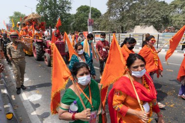 Haridwar, Uttarakhand, Hindistan - 16 Nisan 2021: Hindu kadınlar Ganj Nehri 'nde shahi snaan yemek için geçit töreninde ellerinde bayraklar tutan maskeli kadınlar. Kutsal Maha Kumbhmela etkinliği.