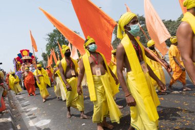 Haridwar, Uttarakhand, Hindistan - 16 Nisan 2021: Maha Kumbhmela etkinliği. Sadhus, sanyasis, dini bayraklı sarı elbiseli rahipler Ganj Nehri 'nde shahi snaan yemek için tören alayında yüksekte yürüyorlardı..