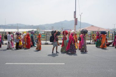 Haridwar, Uttarakhand, Hindistan - 16 Nisan 2021: Hindu kadınlar, Ganj Nehri 'ndeki shahi snaan için bavullarıyla kuyrukta yürüyen parlak yüzlü sariler. Maha Kumbhmela etkinliği.