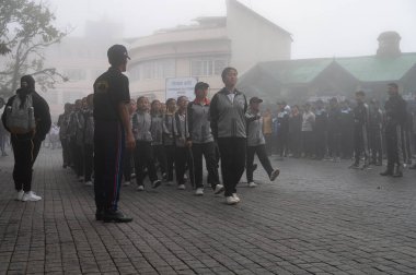 Darjeeling, Batı Bengal, Hindistan -11.08.2023: Bağımsızlık Günü hazırlığı 15 Ağustos 2023. Askeri eğitim için Darjeeling Alışveriş Merkezi 'nin önünden geçen öğrenciler. Sisli bir sabah.