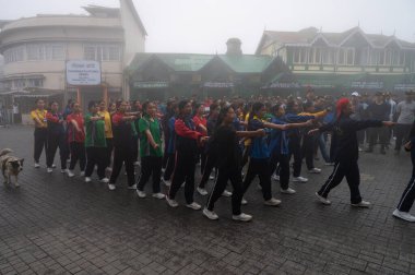 Darjeeling, Batı Bengal, Hindistan -11.08.2023: Sisli sabahta kız öğrenci askeri eğitimi, Bağımsızlık Günü kutlamaları için Darjeeling Alışveriş Merkezi 'nde yürüyen öğrenciler.