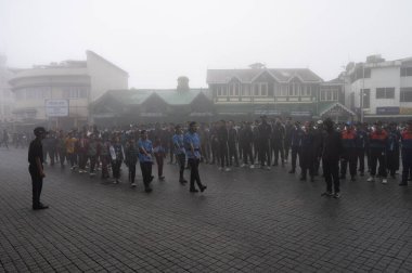 Darjeeling, Batı Bengal, Hindistan -11.08.2023: 15 Ağustos 2023 'te Bağımsızlık Günü kutlamaları için Darjeeling Alışveriş Merkezi' nde yürüyüş yapan öğrenciler, askeri eğitim. Sisli bir sabah.