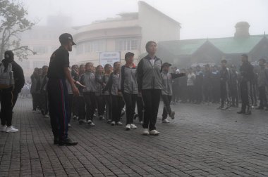 Darjeeling, Batı Bengal, Hindistan -11.08.2023: 15 Ağustos 2023 'te Bağımsızlık Günü kutlamaları için Darjeeling Alışveriş Merkezi' nde yürüyüş yapan öğrenciler, askeri eğitim. Sisli bir sabah.
