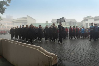 Darjeeling, Batı Bengal, Hindistan -11.08.2023: Sisli sabahta kız öğrenci askeri eğitimi, Bağımsızlık Günü kutlamaları için Darjeeling Alışveriş Merkezi 'nde yürüyen öğrenciler.