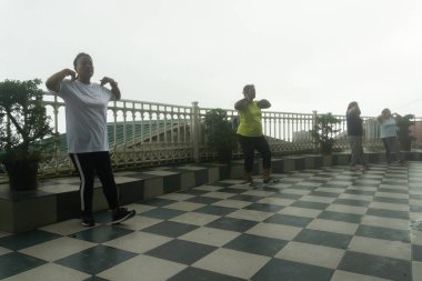 Darjeeling, Batı Bengal, Hindistan - 11.08.2023: Spor yapan genç kadınlar, Darjeeling alışveriş merkezinde sisli bir sabah geçirerek, sağlık bilincine sahip kadınların grup egzersizlerinin faydalarını gösteriyorlar. Genç Himalaya yaşam tarzı.