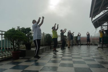 Darjeeling, Batı Bengal, Hindistan - 11.08.2023: Spor yapan genç kadınlar, Darjeeling alışveriş merkezinde sisli bir sabah geçirerek, sağlık bilincine sahip kadınların grup egzersizlerinin faydalarını gösteriyorlar. Genç Himalaya yaşam tarzı.