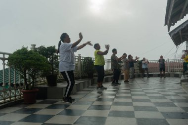 Darjeeling, Batı Bengal, Hindistan - 11.08.2023: Spor yapan genç kadınlar, Darjeeling alışveriş merkezinde sisli bir sabah geçirerek, sağlık bilincine sahip kadınların grup egzersizlerinin faydalarını gösteriyorlar. Genç Himalaya yaşam tarzı.