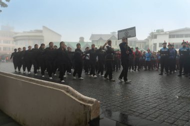 Darjeeling, Batı Bengal, Hindistan -11.08.2023: Sisli sabahta kız öğrenci askeri eğitimi, Bağımsızlık Günü kutlamaları için Darjeeling Alışveriş Merkezi 'nde yürüyen öğrenciler.
