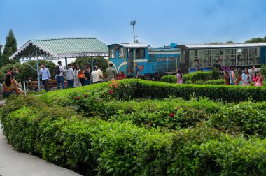 Darjeeling, Batı Bengal, Hindistan - 20.08.2023: Hint ordusunun savaş anıtı Batasia döngüsünden geçen Diesel Oyuncak treni. Darjeeling Himalaya Demiryolu, Unesco dünya mirası alanı, Himalaya musonu.