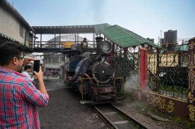 Darjeeling, Batı Bengal, Hindistan-20.08.2023: Oyuncak treninin Buhar makinesinden çıkan sıcak buharın fotoğrafını çeken turist, Himalayalar 'da, Ghum İstasyonu' nda yolculuğa hazırlanıyor. Unesco sitesi.