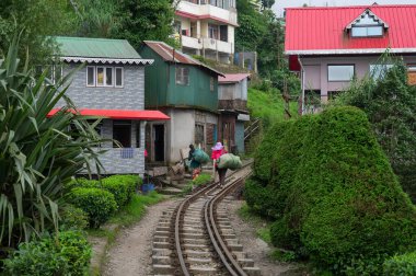 Darjeeling, Batı Bengal, Hindistan-20.08.2023: Batasia Loop 'ta Himalayalar' dan geçmek için oyuncak trenler için dar ölçü çizgisi üzerinde yürüyen iki kadın. UNESCO dünya mirası sahası.