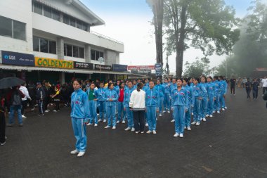 Darjeeling, Batı Bengal, Hindistan -11.08.2023: Sisli sabahta liseli kızlar askeri eğitim, Bağımsızlık Günü kutlamalarına hazırlanmak için Darjeeling Alışveriş Merkezi 'nde geçmişteki yürüyüşlere hazırlanan öğrenciler.