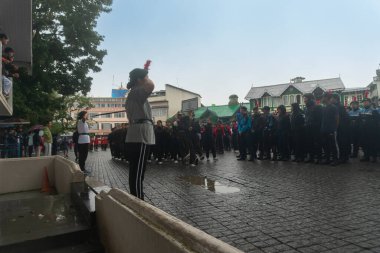 Darjeeling, Batı Bengal, Hindistan -11.08.2023: Sisli sabahlarda liseli kızlar için askeri eğitim, Bağımsızlık Günü kutlamaları için Darjeeling Alışveriş Merkezi 'nin önünden geçen öğrenciler.