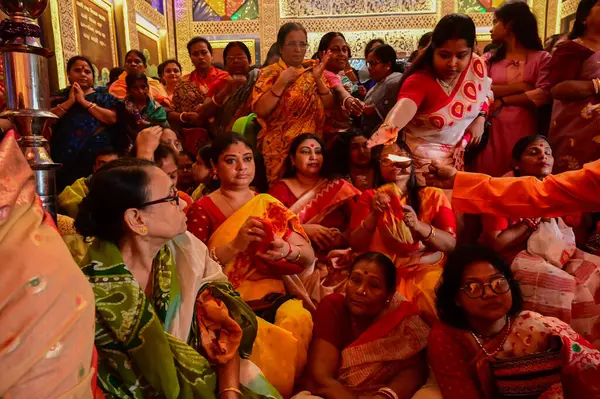 Howrah, Batı Bengal, Hindistan -11.10.2024: Hintli kadınlar kutsal radip, lamba, sondhipujo, puja arasında Ashtami ve nabami 'yi ısıtmak için uzanırlar. Geleneksel Bengali puja ritüeli.