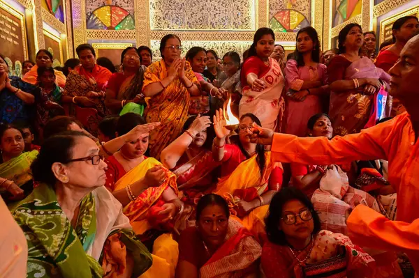 Howrah, Batı Bengal, Hindistan -11.10.2024: Hintli kadınlar kutsal radip, lamba, sondhipujo, puja arasında Ashtami ve nabami 'yi ısıtmak için uzanırlar. Geleneksel Bengali puja ritüeli.