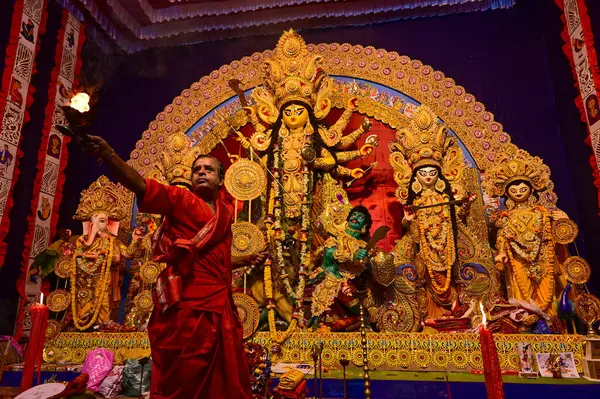 Howrah, Batı Bengal, Hindistan -11.10.2024: Hindu purohit tanrıça Durga 'ya tapma aydınlatma diya, pradip, kutsal lamba nabami puja sırasında. Geleneksel Durga puja ritüeli.