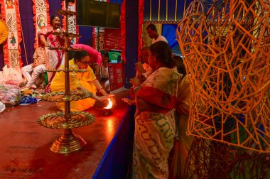 Howrah, Batı Bengal, Hindistan -11.10.2024: Hindu kadınlar kutsal pradip, lamba, sondhipujo, ashtami ve nabami arasındaki puja 'yı sıcak tutuyorlar. Geleneksel Bengali puja ritüeli.