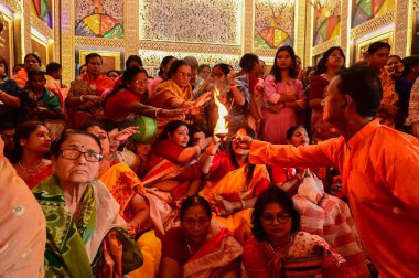 Howrah, Batı Bengal, Hindistan -11.10.2024: Hintli kadınlar kutsal pradip, lamba, sondhipujo, puja, ashtami ve nabami arasında ısınmak için uzanıyorlar. Geleneksel Bengali puja ritüeli.