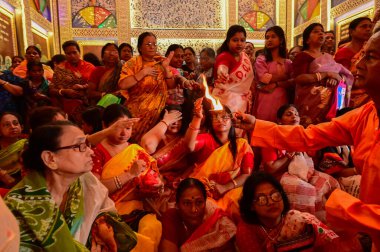 Howrah, Batı Bengal, Hindistan -11.10.2024: Hintli kadınlar kutsal pradip, lamba, sondhipujo, puja, ashtami ve nabami arasında ısınmak için uzanıyorlar. Geleneksel Bengali puja ritüeli.